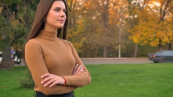 Portret van aantrekkelijke jonge brunette meisje lopen en gebaren vredesteken met glimlach op herfst park achtergrond. — Stockvideo