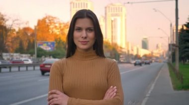 Ciddi beyaz esmer alçakgönüllülükle kollarını ile kamera içine seyretme portre yol arka plan üzerinde çarpı işareti.