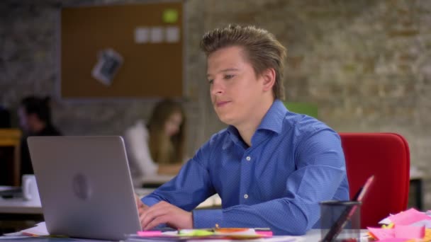 Retrato de homem de negócios loiro de meia-idade na frente do laptop enfrentando problemas e irritantemente reclinado na cadeira no escritório . — Vídeo de Stock