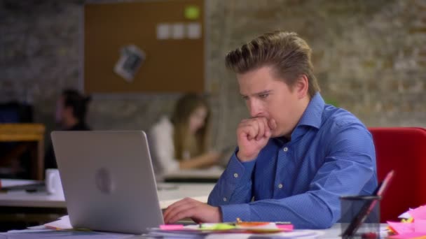 Портрет блондина среднего возраста, работающего с ноутбуком и кашляющего в офисе . — стоковое видео