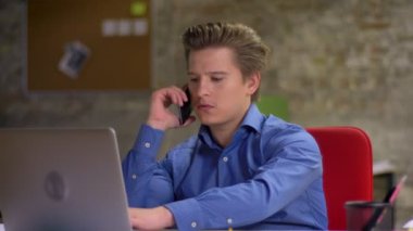 Telefonda konuşmak ve dizüstü bilgisayar kullanma office orta yaşlı sarışın işadamı portresi.