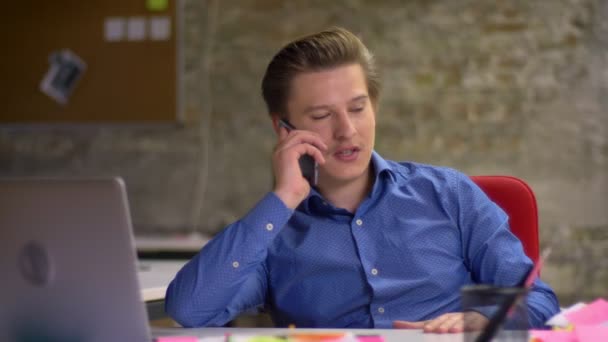 Retrato de homem de negócios loiro de meia-idade falando no celular e levantando seus danos alegremente no escritório . — Vídeo de Stock