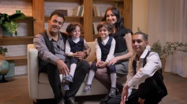 Arapça aile kanepede oturan ve oturma odasında bir gülümseme ile fotoğraf makinesi içine izlerken.
