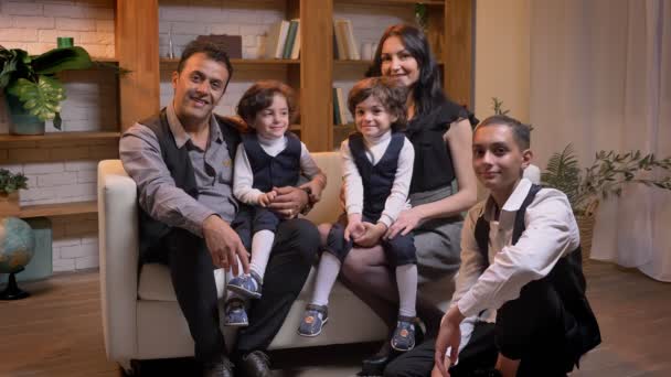 Arabic family sitting on sofa and watching into camera with smile in living room. — Stock Video