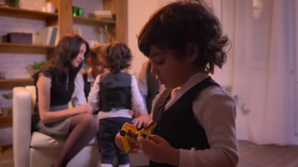 Крупним планом портрет маленького арабського хлопчика, який грає з іграшкою-роботом з батьками на фоні . — стокове відео
