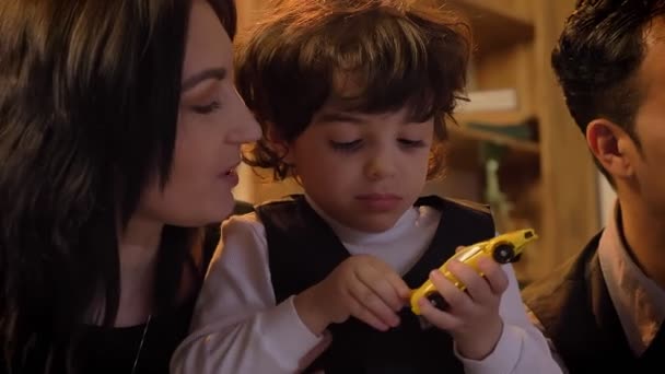 Nahaufnahme Porträt arabischer Eltern, die mit ihrem kleinen lockigen Sohn spielen und im Wohnzimmer in die Kamera lächeln. — Stockvideo