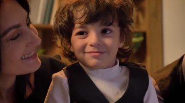 Yakın çekim portre bir öpüşme ve küçük kıvırcık kafalı oğlu ile oturma odasında oynarken Arapça anne.