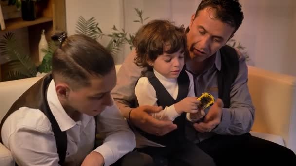 아랍어 아버지와 그의 십 대 아들 들이 소파에 앉아 놀고 트윈 거실에서 곱슬 머리 소년. — 비디오