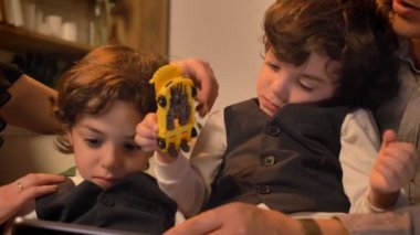 Yakın çekim tutmak oyuncak tablet dikkatle izliyor iki Arapça kıvırcık kafalı ikiz erkek portresi.