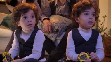 İki Arap kıvırcık kafalı ikiz dikkatle Tv izlerken oturma odasında katta oturan portresi.
