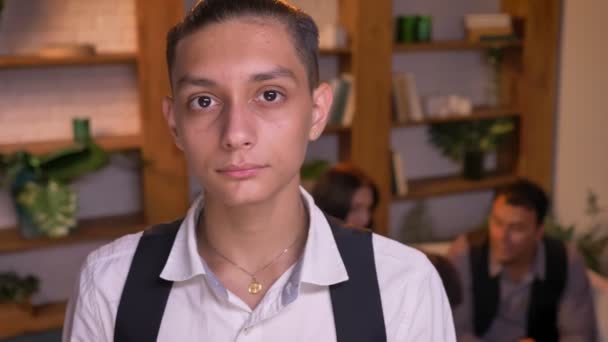 Närbild porträtt av arabiska tonårspojke allvarligt titta direkt i kameran med sin familj på bakgrund. — Stockvideo