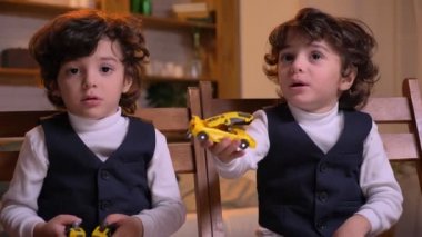 İki Arap kıvırcık kafalı ikiz oturma odasında dikkatle kamera izliyor ve konuşmaya sandalyelere oturan portresi.