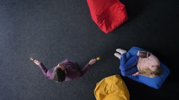 Top-shot of man jumping rope and woman playing with ball sitting on multicoloured soft bag. — Stock Video