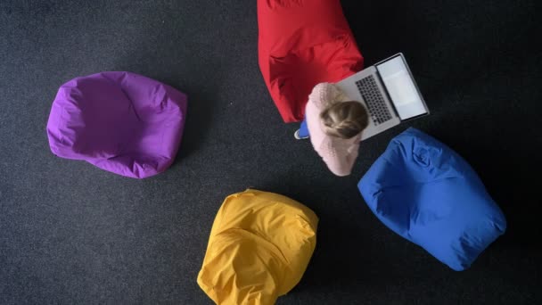 Top-shot of young woman walking and working with laptop on multicoloured bags background. — Stock Video