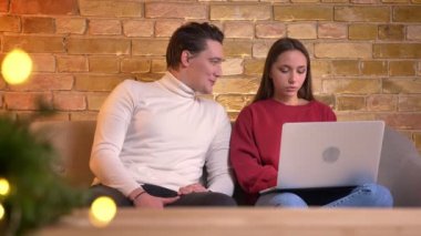 Laptop ile çalışma ve onun yanında ev ortamında kanepede oturan arkadaşı ile gülüyor cyoung esmer kız portresi