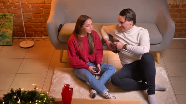 Zblízka pohled shora dolů mluví mladí kavkazské přátelé sedí na koberci s vínem v útulné domácí vánoční atmosféře. — Stock video