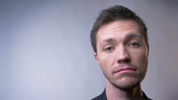 Closeup of face of attractive caucasian man looking straight at camera listening and nodding with a serious facial expression — Stock Video