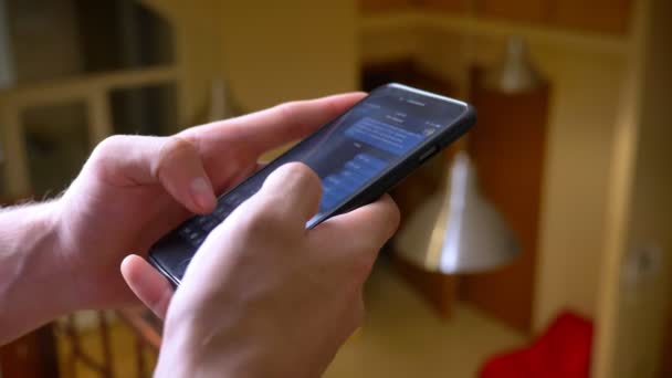 Gros plan des mains tapant dans le messager à l'aide d'un smartphone sur fond de pièce . — Video