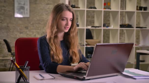 Portret van blonde Kaukasische zakenvrouw werkt aandachtig met laptop in office. — Stockvideo