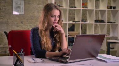 Dikkatle dizüstü Office ile çalışan sarışın beyaz işkadını portresi yukarı doğru thoghtfully saatler.