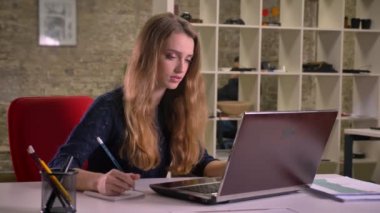 Dikkatle laptop ile çalışmaya ve notlar ofiste yapma sarışın beyaz işkadını portresi.
