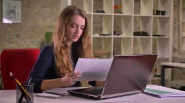 Sarışın çekici beyaz işkadını dikkatle istatistik raporları Office ile çalışan portresi.