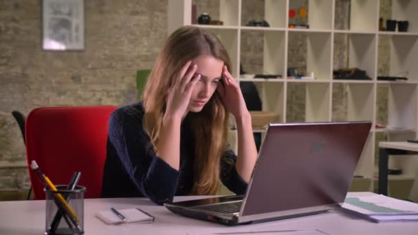 Porträt der blonden kaukasischen Geschäftsfrau, die im Büro mit Laptop arbeitet, steht vor Schwierigkeiten und legt verwirrt ihre Hände auf die Hand. — Stockvideo