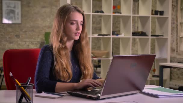 Retrato de loira atraente mulher de negócios caucasiana falando em videochat usando laptop no escritório . — Vídeo de Stock