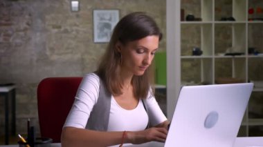 İyi haber alma ve bir zafer ile gülümseyen dizüstü bilgisayarda yazarak çekici kadın ofis çalışanı