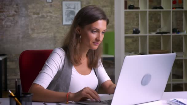 Dizüstü bilgisayarda tarama çekici kadın ofis çalışanı mutlu heyecanlanıyor ve kollarını sevinç yükseltir — Stok video