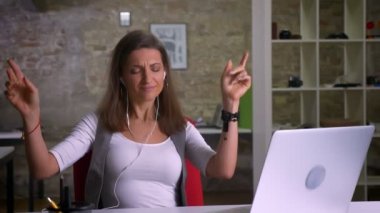 Müzik ve dizüstü kulaklık olmak önünde oturan sevinçle dans çekici çok güzel kadın ofis çalışanı