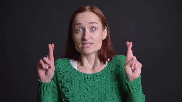 Close-up van aantrekkelijke Kaukasische vrouw met haar vingers gekruist en op zoek naar camera met angstig en hoopvol gelaatsuitdrukking — Stockvideo