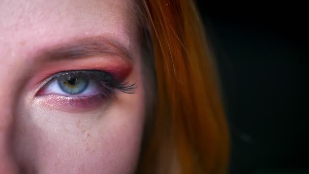 Primer plano de maquillaje impresionante ojo azul con tonos rosados pestañas largas y purpurina en el fondo negro — Vídeos de Stock