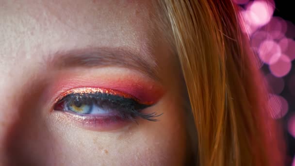 Крупный план удивительного женского синего глаза макияж с розовыми оттенками и золотой глазной линии. Глаз смотрит в сторону, а затем поворачивается прямо к камере — стоковое видео