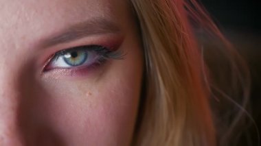 Gizemli çarpıcı kadın mavi gözler makyaj pembe gölgeli ve koyu arka plan ile altın eyeline closeup.