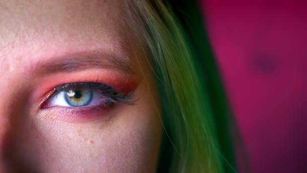 Primer plano de maquillaje hermoso ojo femenino con tonos rosados y eyeline de oro. Pelo verde sobre el fondo rosa de hadas — Vídeos de Stock