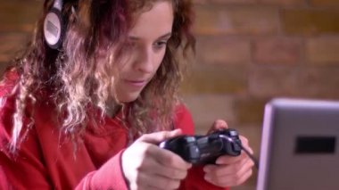 Yakın çekim portre genç kadın Blogger aktif video bricken duvar arka plan üzerinde joystick kullanarak oyun oynarken.