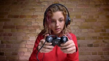 Yakın çekim portre bricken duvar arka plan üzerinde joystick ile oynamak kulaklık dahil ve ilgili Blogger.