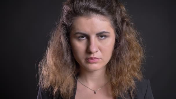 Nahaufnahme Porträt einer übergewichtigen kaukasischen Frau, die direkt und ruhig in die Kamera auf schwarzem Hintergrund blickt. — Stockvideo