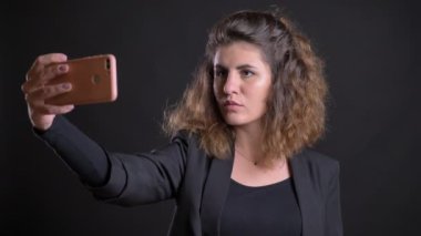Selfie-fotoğrafları yapma kilolu kafkas kadın yakın çekim portre siyah arka plan üzerine smartphone kullanarak.