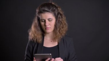 Tablet ile çalışan konsantre kilolu beyaz kadın portresi yakın çekim yeşil ekran siyah arka plan üzerinde gösterir.