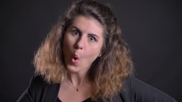 Close-up portrait of overweight caucasian woman happily making strange faces watching into camera on black background. — Stock Video