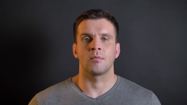 Close-up portrait of middle-aged caucasian man watching calmly and directly into camera on black background. — Stock Video