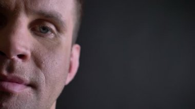 Orta yaşlı beyaz adam sakin bir şekilde gülümseyerek ve doğrudan içine kamera siyah arka plan üzerine izlerken yakın çekim yarı-portre.