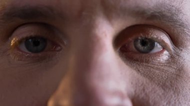 Yakın çekim göz-portre sakin bir şekilde izlerken Orta yaşlı beyaz adamın ve doğrudan içine kamera siyah arka plan üzerine.