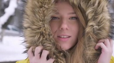 Kürk başlıklı kış sokak arka plan üzerinde kamera içine gülümseyerek poz güzel genç beyaz kız portresi yakın çekim.