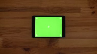 Hızla üst yatay tablet ile yeşil ekran görüntüsünü ahşap Resepsiyon arka plan üzerinde yakınlaştırma.