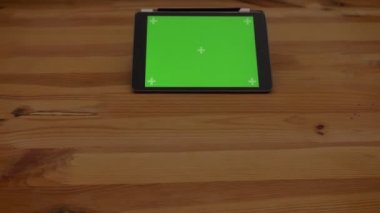 Yavaş yavaş yaklaşan yakın çekim yatay tablet ile ahşap Resepsiyon zemin üzerine yeşil perde atış.