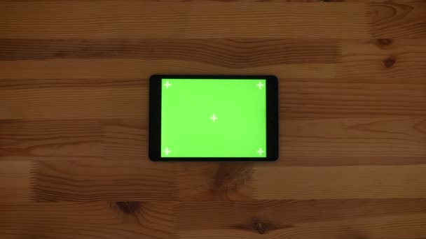 Top shot de tablet horizontal com tela verde no fundo da mesa de madeira . — Vídeo de Stock