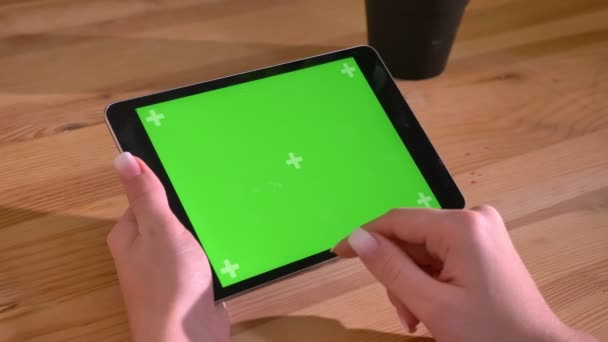 水平であるタブレットと木製のデスクの背景に緑色の画面でスワイプの手のクローズ アップ ショット. — ストック動画